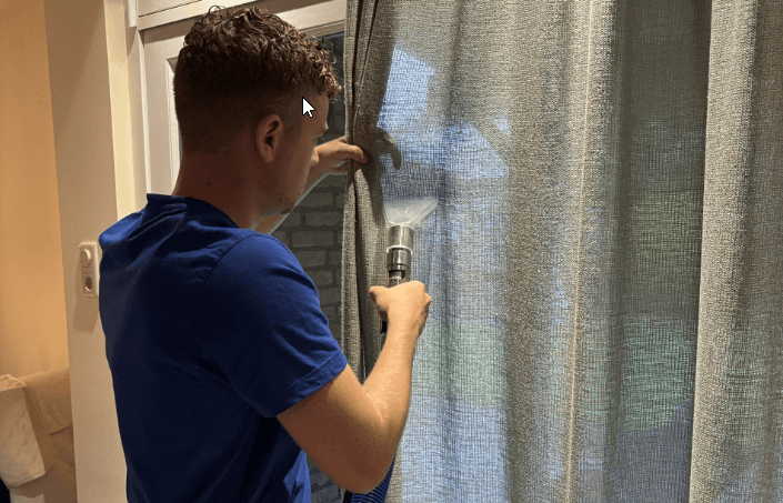 Specialist reinigt een raambekleding met sproei-extractie