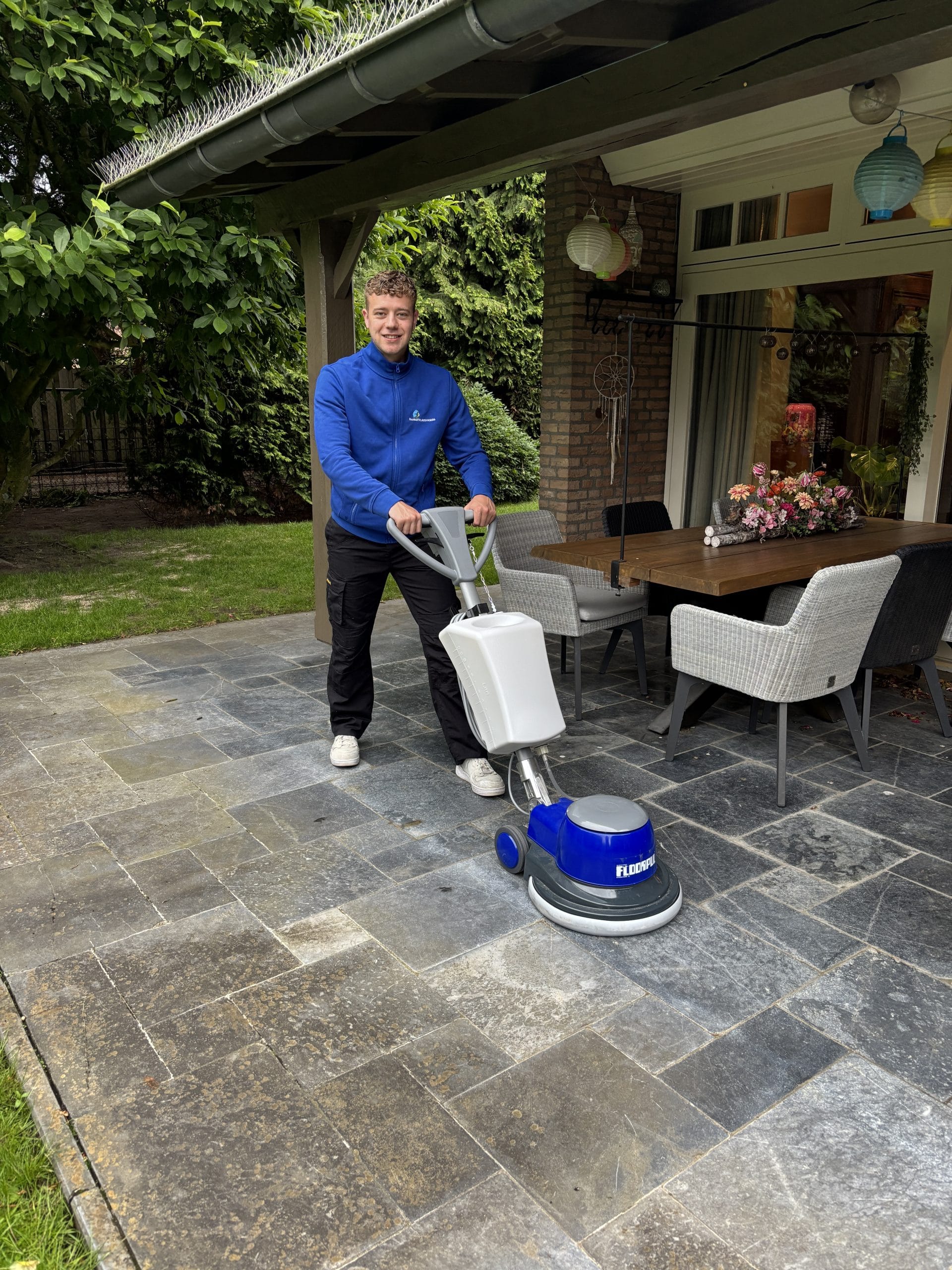 Rowan reinigt een terras met de schrobmachine