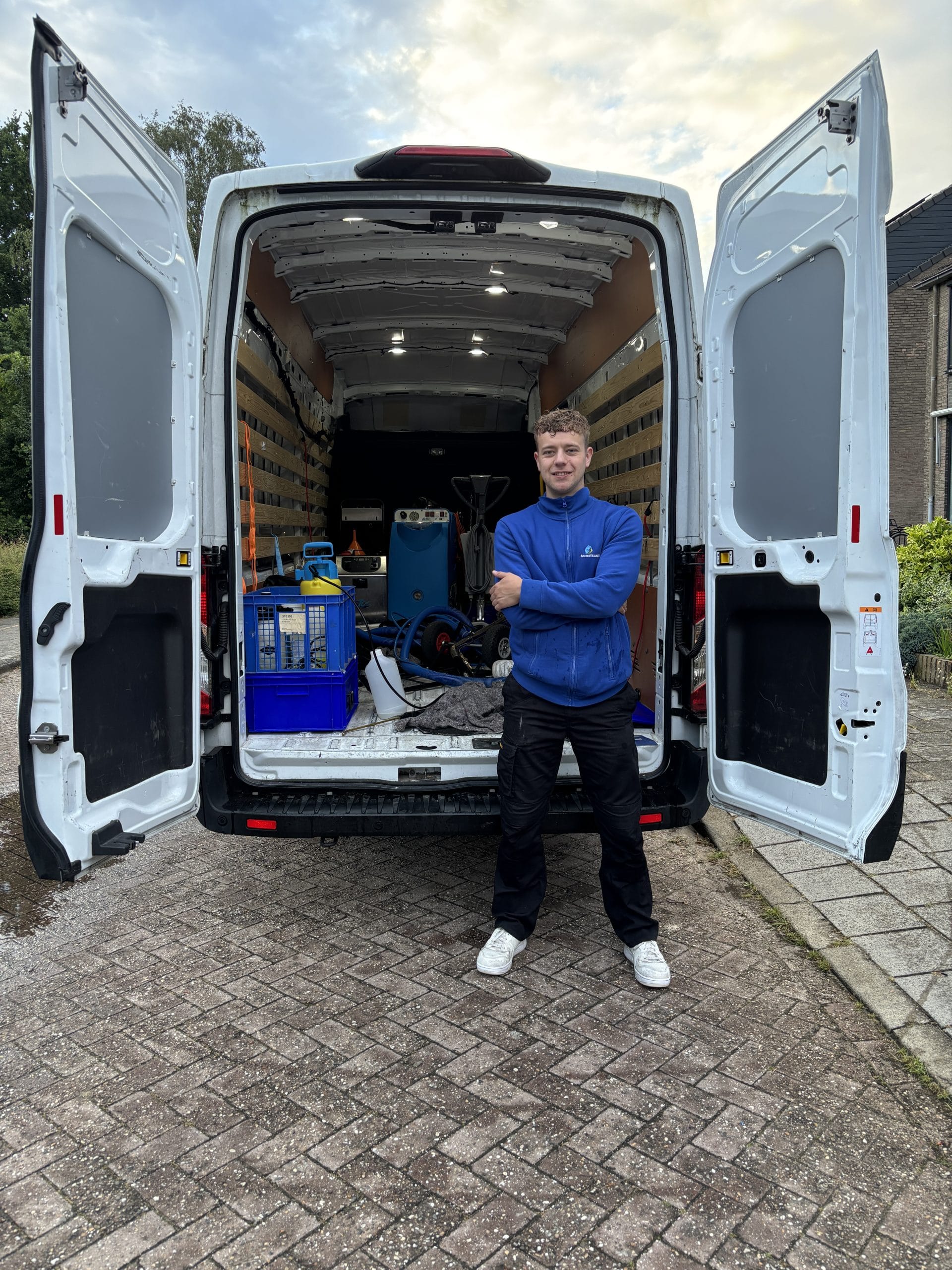 Dennis bij de geopende bus met alle reinigingsapparatuur