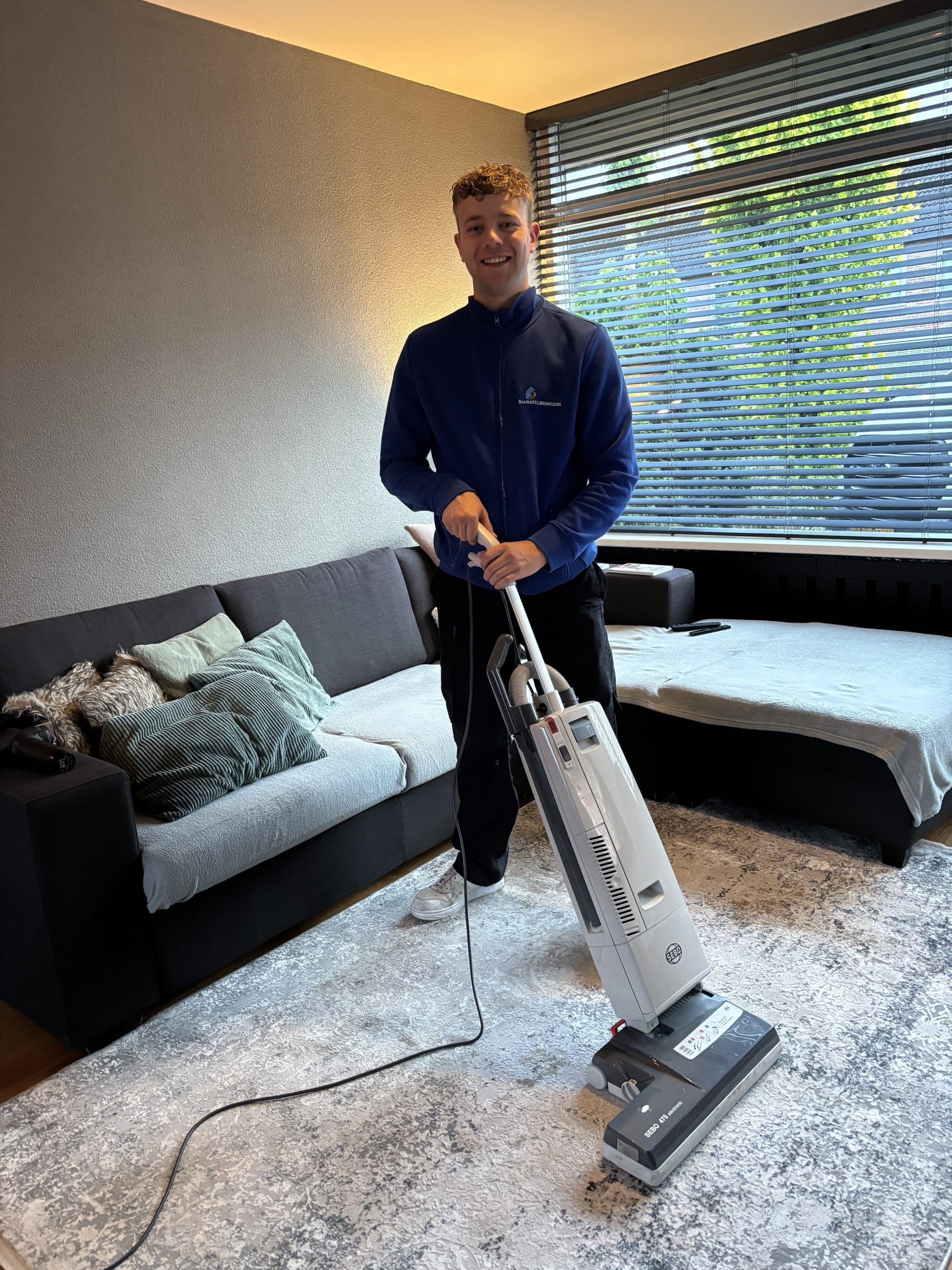 Dennis reinigt vloerbedekking naast de bank
